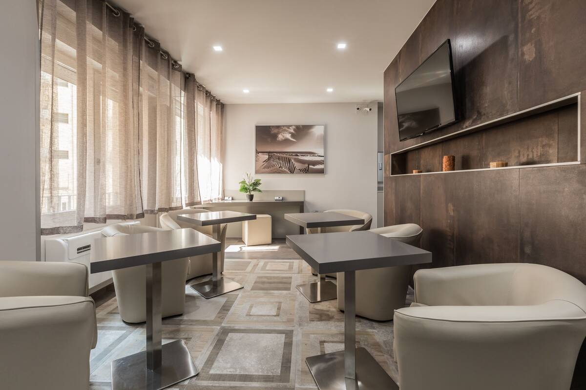 Una sala de estar moderna con un televisor de pantalla plana grande, un comedor con mesa y sillas, y un rincón de descanso acogedor con sofás.