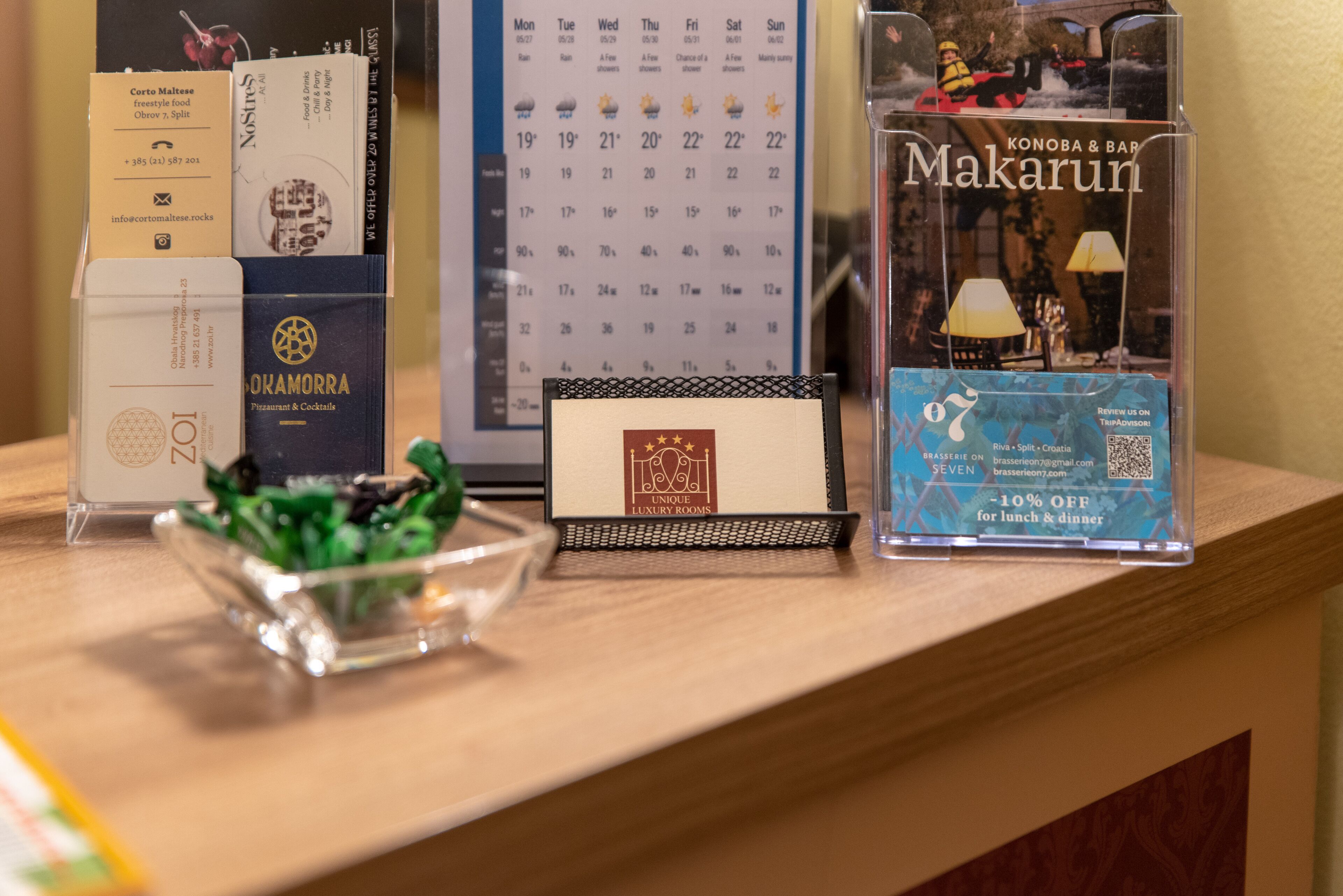 Una reception hoteliera con diversi materiali promozionali, tra cui un calendario, un biglietto da visita e una brochure.