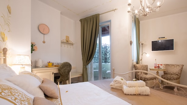 A hotel room with a bed, a desk, a chair, a TV, and a balcony with a view.