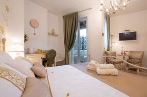 Habitación de hotel con cama, escritorio, silla, televisor y balcón con vistas.