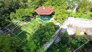 An aerial view of a garden with a gazebo, a stone wall, and a staircase leading up to a building.