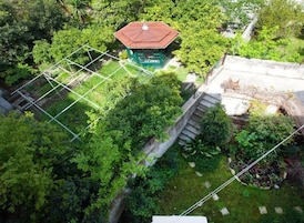 An aerial view of a garden with a gazebo, a stone wall, and a staircase leading up to a building.