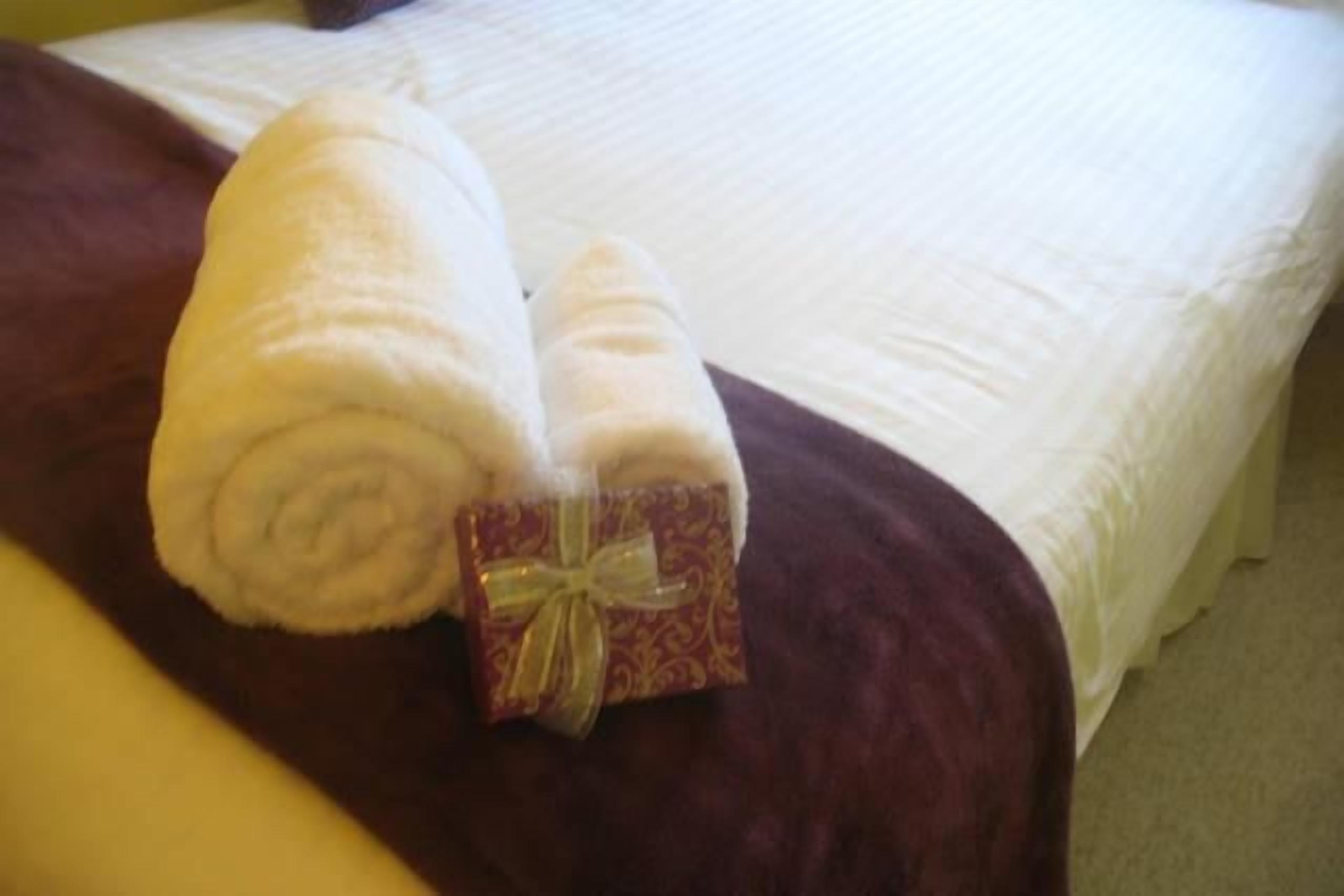 A bed with a white bedspread and a brown blanket.