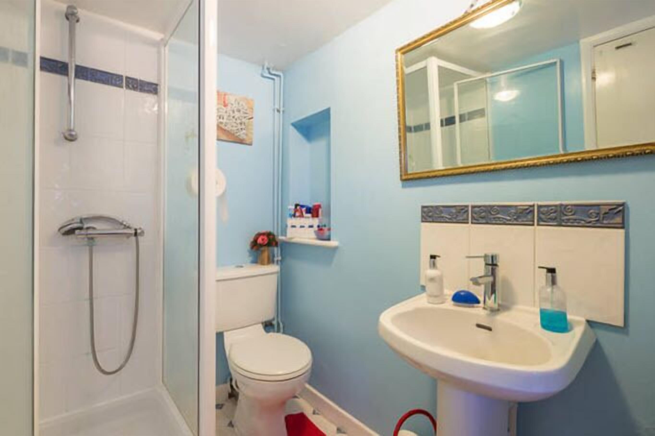 Ein Badezimmer mit Dusche, Toilette, Waschbecken und Spiegel.