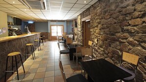 A restaurant with a stone wall, tiled floor, bar area, and several tables and chairs. - Hotel Casa Palacio (Montanejos)