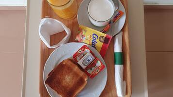 Bandeja con tostadas, jugo, leche y un sobre de café instantáneo.