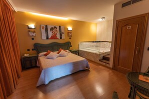 Quarto de hotel com uma cama grande, banheira, porta de madeira e uma pequena mesa.