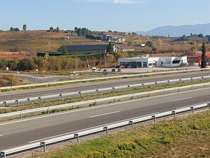 Une autoroute à plusieurs voies, dotée de glissières de sécurité et où circulent quelques véhicules. On aperçoit des bâtiments en arrière-plan, notamment un restaurant et une station-service.