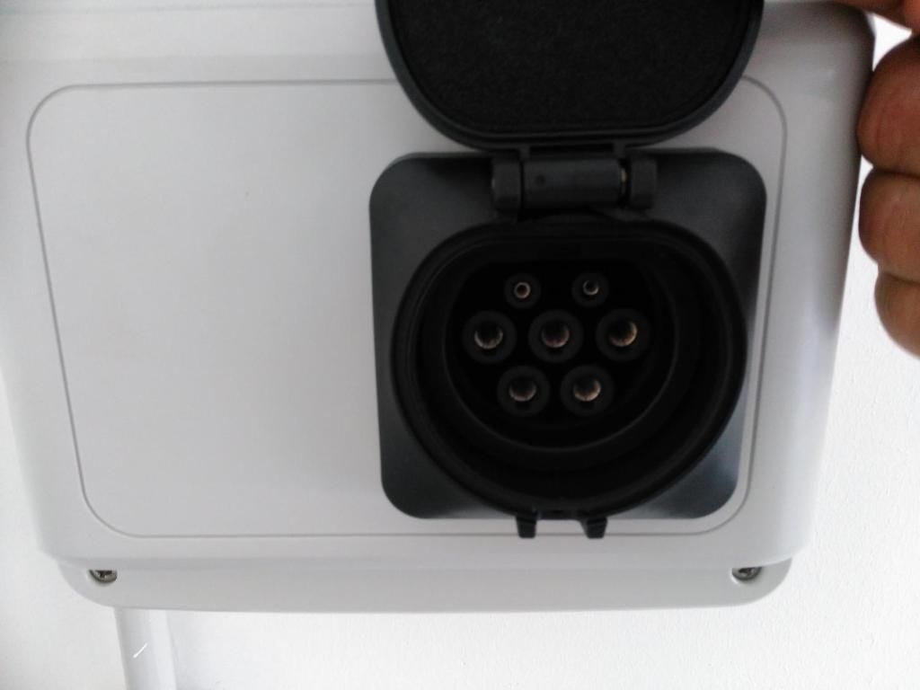 A white device with a black circular port and a hinged cover.