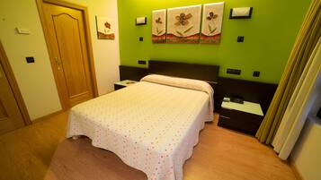 Una habitación de hotel con cama, suelo de madera, paredes verdes y una obra de arte en la pared.
