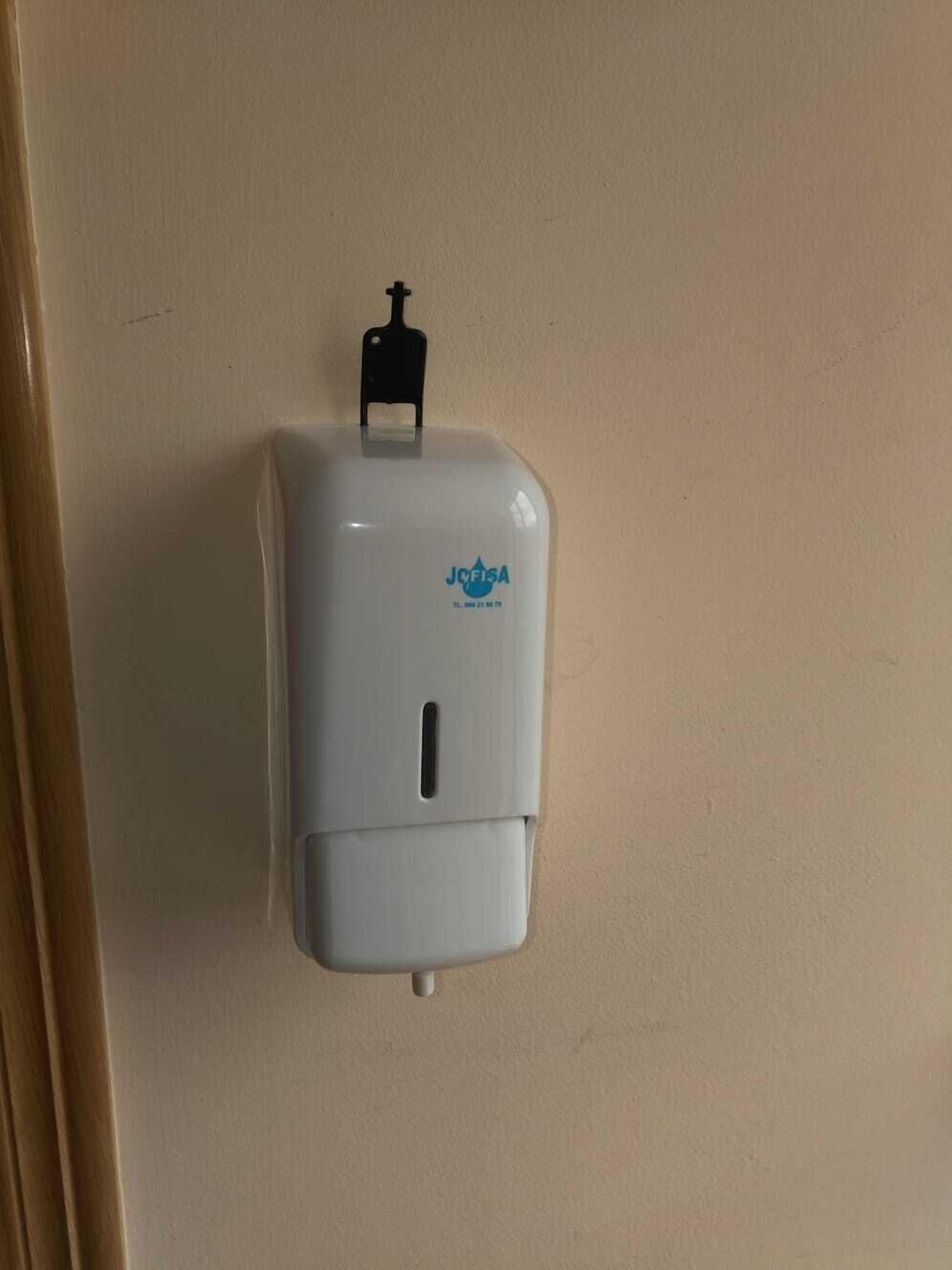 Un distributeur de gel hydroalcoolique mural, avec un dessus noir et un logo bleu.