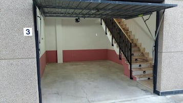 A stairwell with a red and white wall, a concrete floor, and a metal railing.