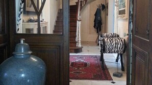 A grand entrance with a chandelier, a zebra statue, and a large vase. - Les Lamartine (Le Mans)