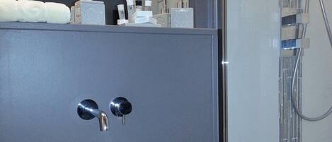 Un baño moderno con un lavabo de vidrio, un cabezal de ducha manual y un espejo.
