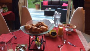A dining area with a table set for breakfast, including croissants, juice, and condiments. - Les Lamartine (Le Mans)