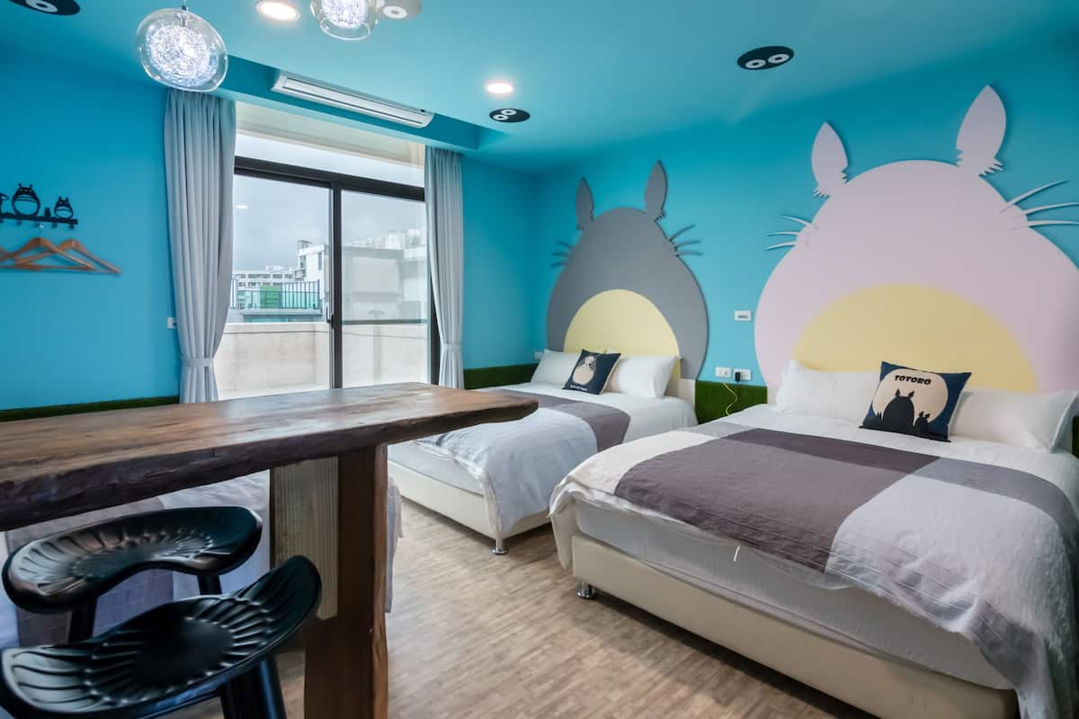 A hotel room with two beds, a wooden table, and black chairs.