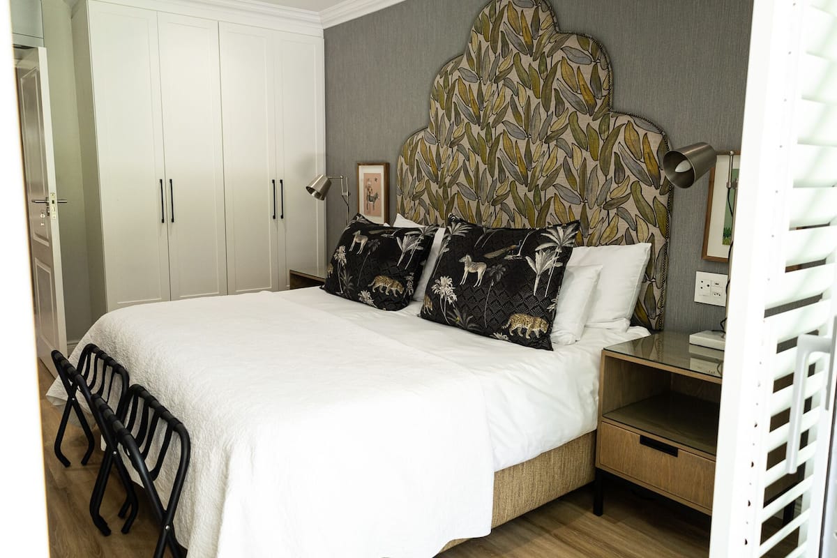 A neatly arranged bedroom with a bed, bedside tables, and a wardrobe.