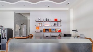 A modern reception desk with a clean, minimalist design, featuring a counter, a coffee machine, and a digital screen. - Oriental Blue Smart Stay (Taitung)