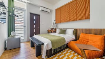 Quarto com cama, escrivaninha, cadeira, janela com persianas e ar-condicionado fixado na parede.