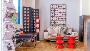 A modern living room with a sofa, red stools, a coffee table, and a large abstract painting on the wall. - Oriental Blue Smart Stay (Taitung)