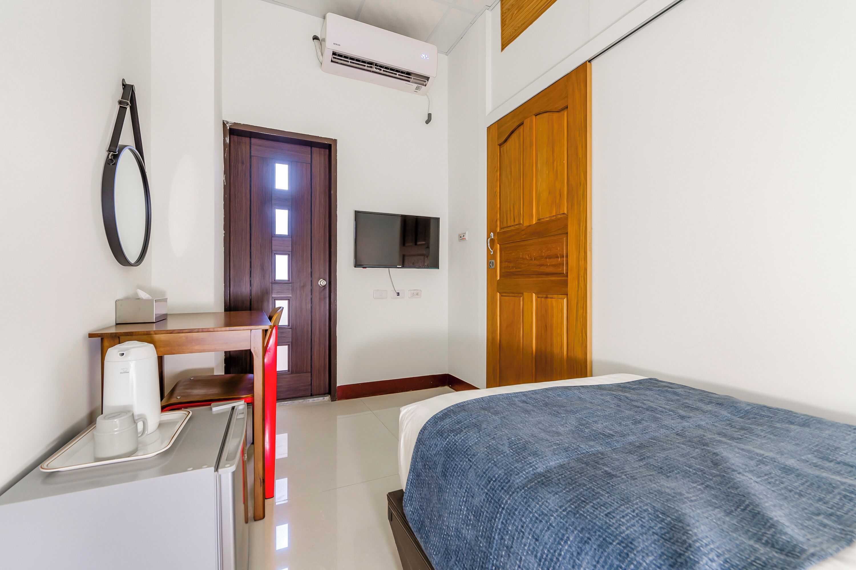 Una camera d'hotel con un letto, una scrivania con una macchina per il caffè, una televisione e una porta in legno.