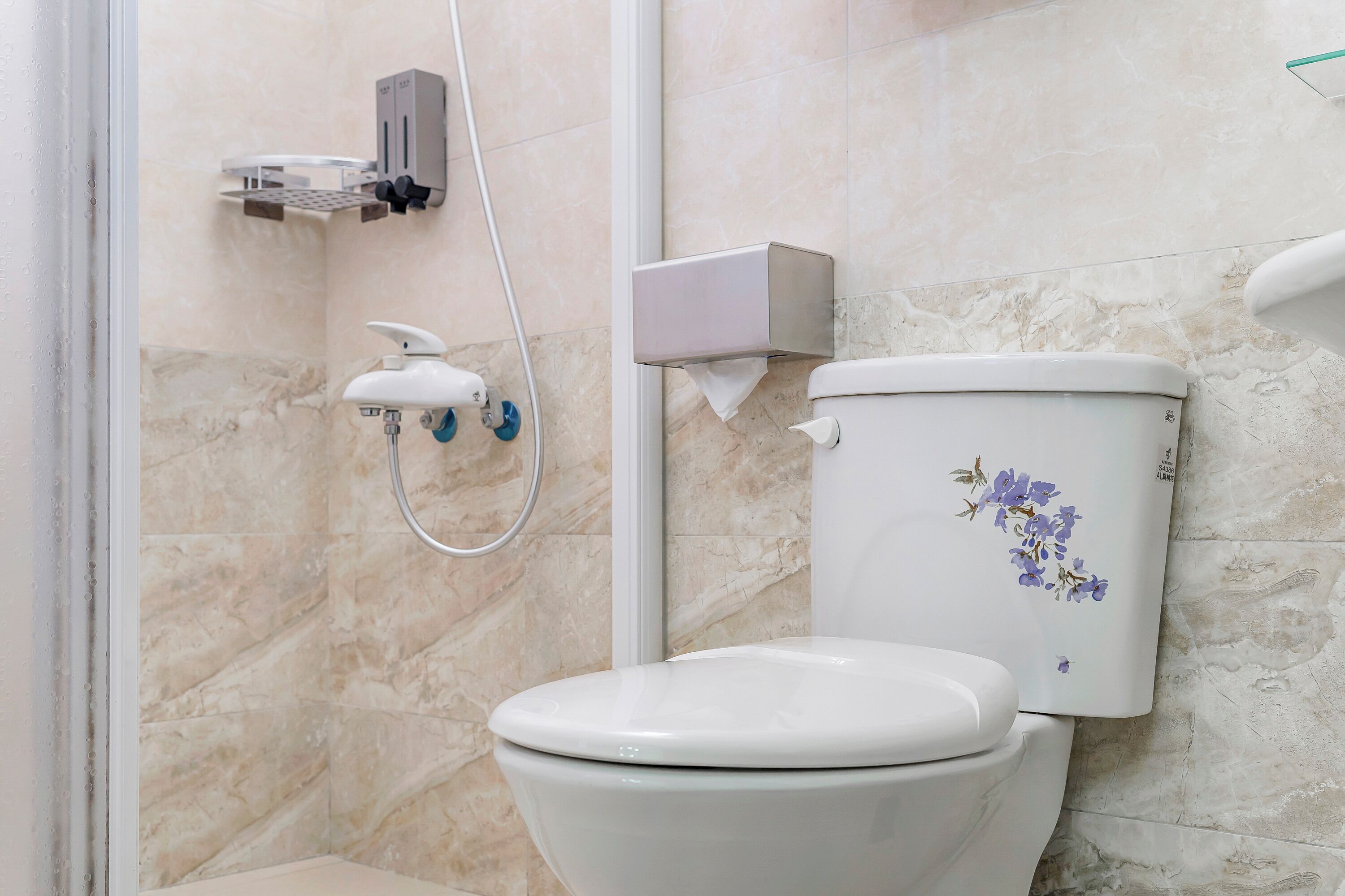 Une salle de bain équipée de toilettes, d’un sèche-mains et d’un distributeur de savon mural.
