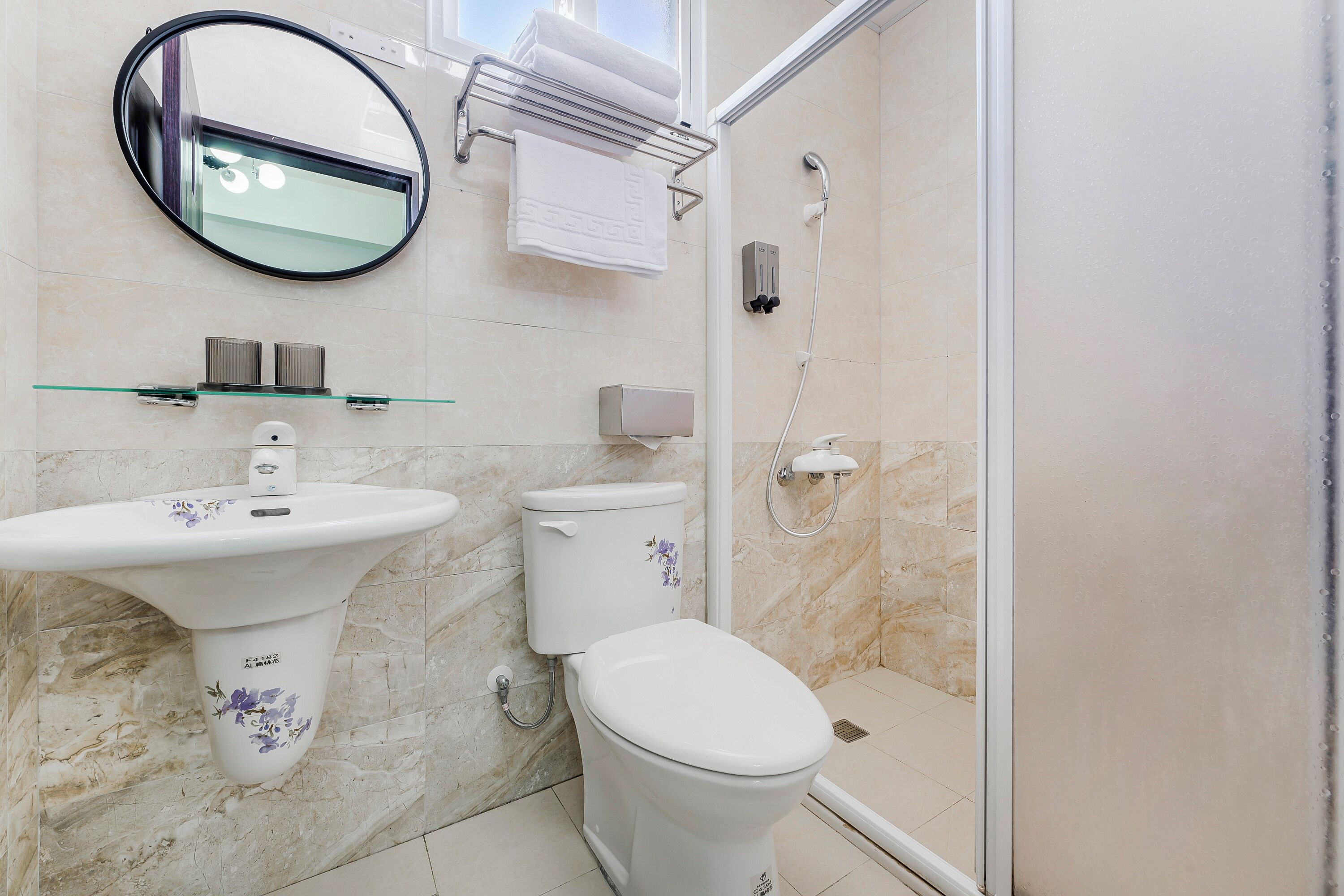 Um banheiro moderno com pia de pedestal, vaso sanitário e box de vidro.