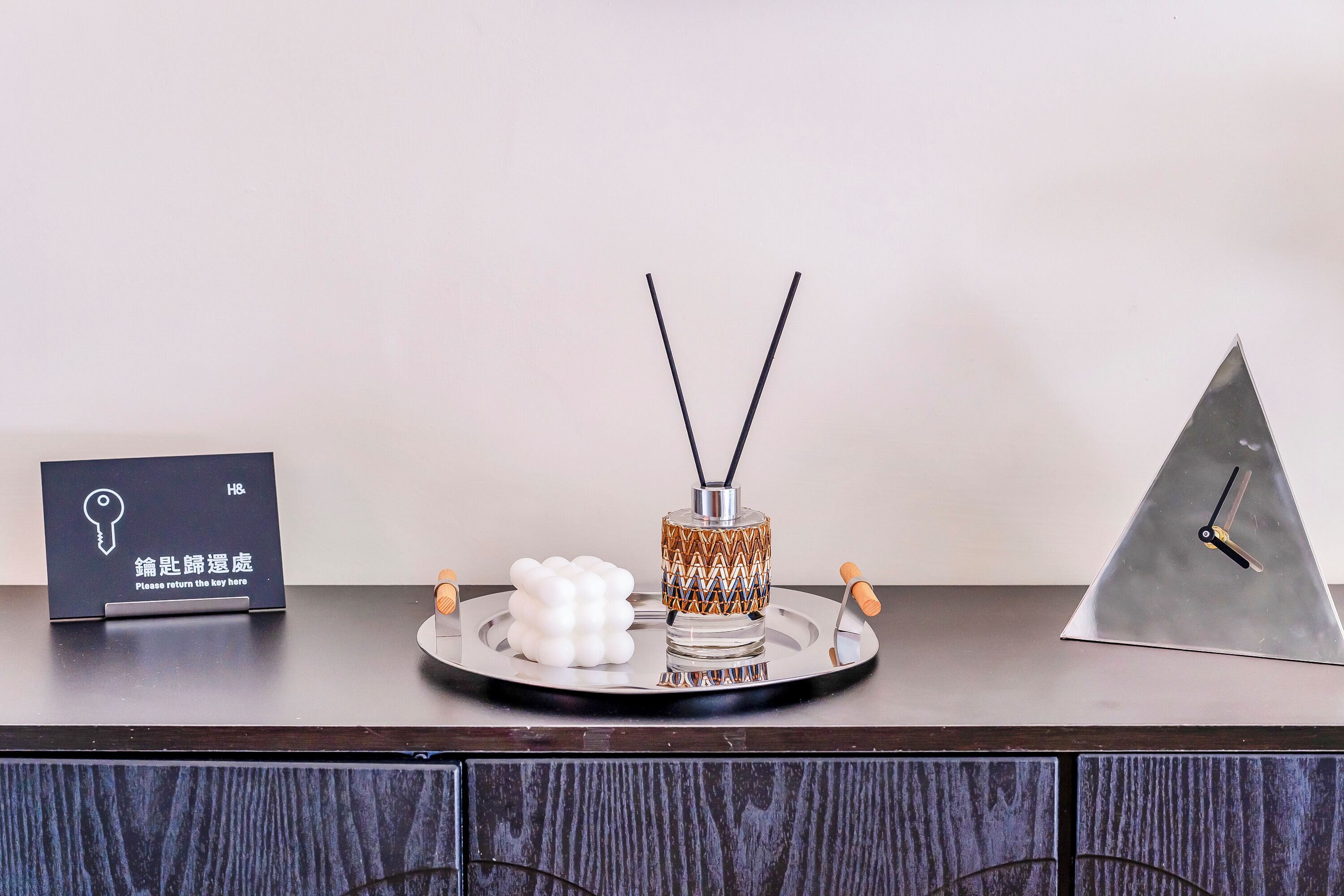A hotel reception desk with a key card holder, a decorative bottle, and a clock.