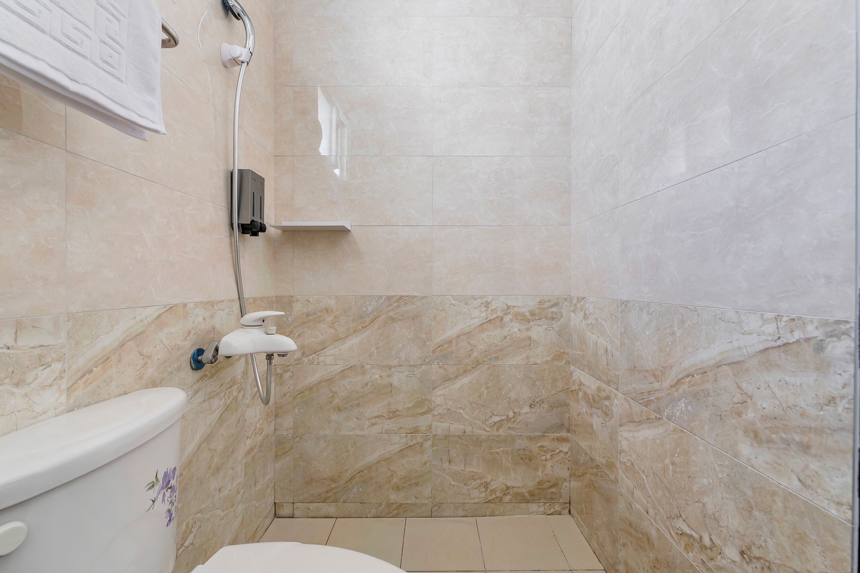 A bathroom with a shower, toilet, and marble walls.