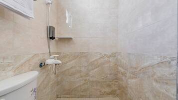 A bathroom with a shower, toilet, and marble walls.