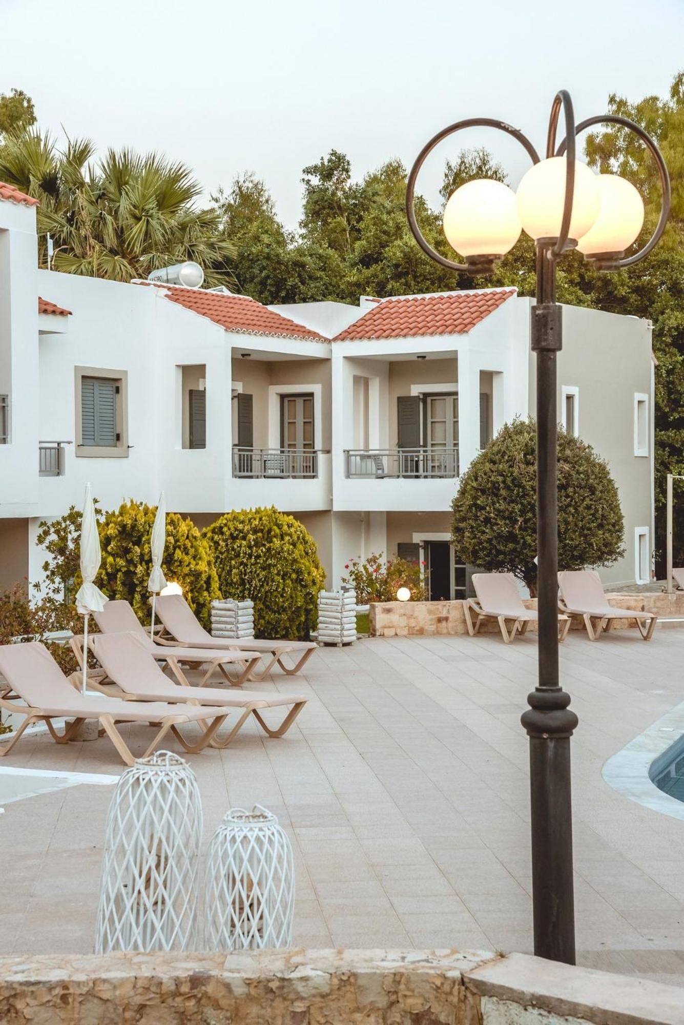 Um edifício moderno com área de piscina, incluindo cadeiras de descanso e um poste de luz.
