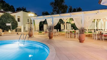 Una piscina al aire libre, sombrillas, sillones reclinables de piscina