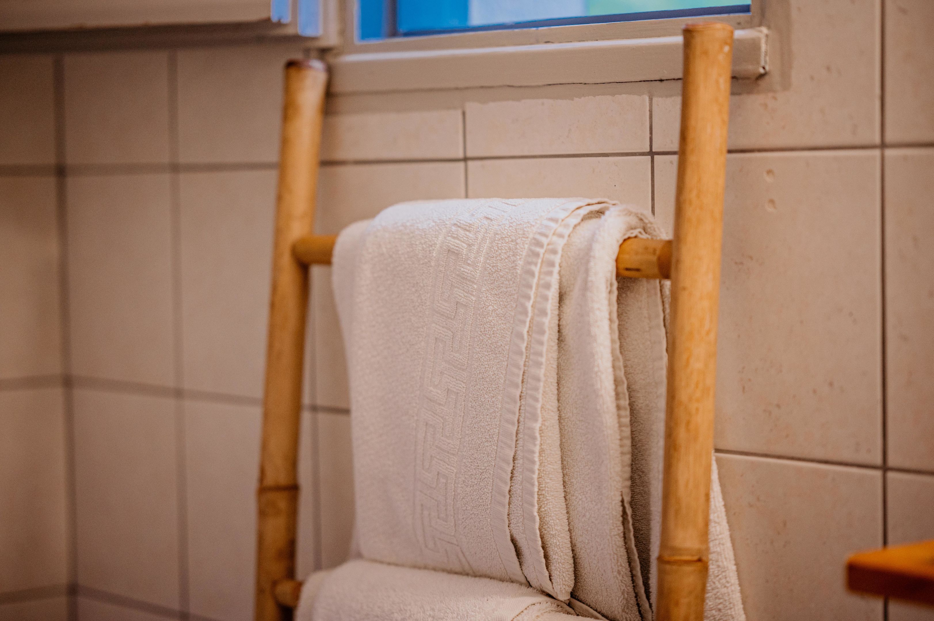 Een badkamer met een houten handdoekrek en een witte handdoek.