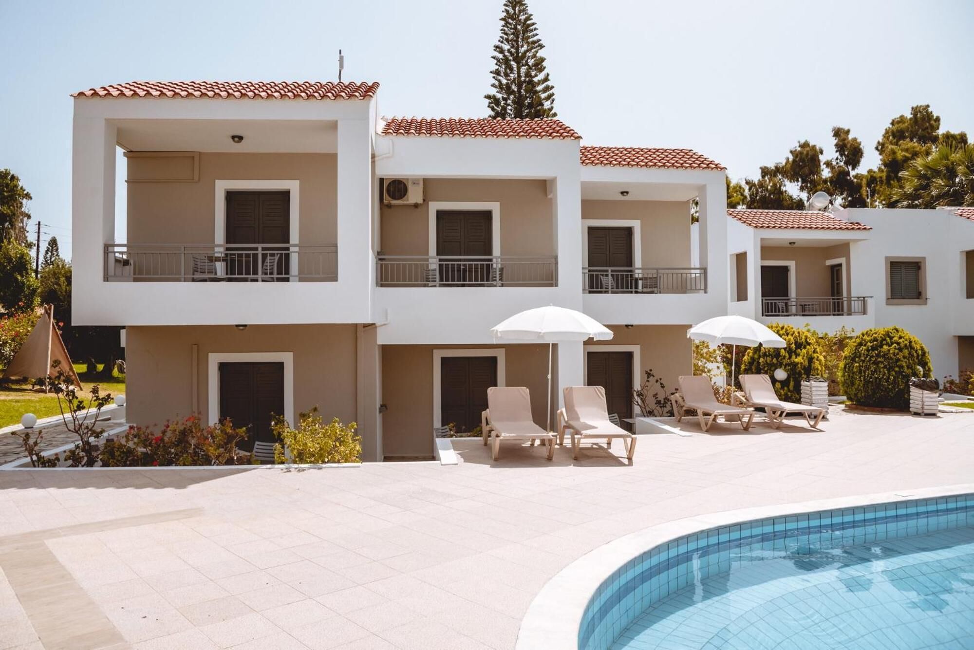 A modern hotel with a swimming pool, multiple balconies, and outdoor seating areas.