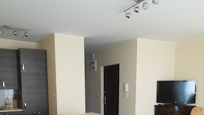 Een moderne keuken met donkere kastjes, een centraal eiland en een eethoek met een houten tafel en stoelen.