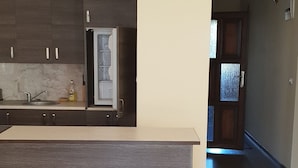 Een moderne keuken met donkerhouten kastjes, een marmeren aanrechtblad en een geïntegreerde koelkast.