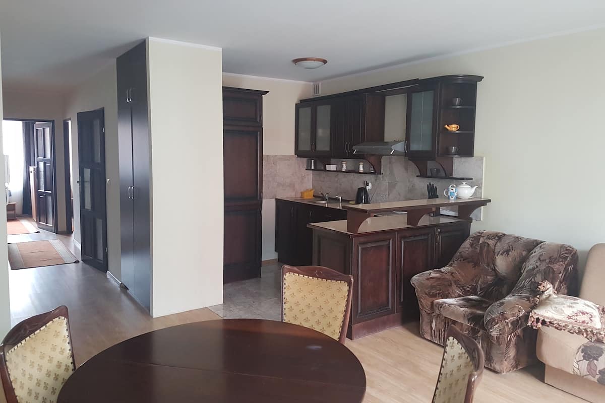 A modern kitchen with dark wooden cabinets, a central island, and a dining area with a round table and chairs.
