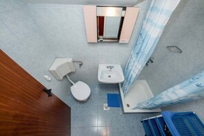 Une salle de bain avec des toilettes, un lavabo et une douche.