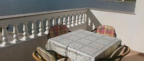 A balcony with a table and chairs overlooking a body of water.