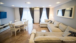 A modern living room with a dining table, sofa, and TV. - Merkel Villa Apartamente (Wiesbaden)
