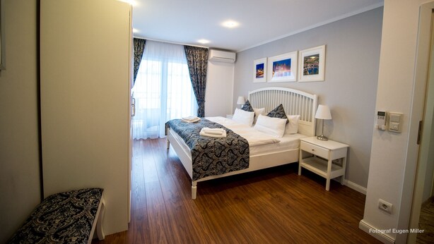 A bedroom with a bed, bedside tables, a window with curtains, and wall-mounted artwork. - Merkel Villa Apartamente (Wiesbaden)