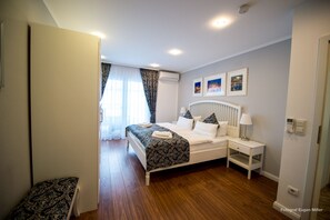 A bedroom with a bed, bedside tables, a window with curtains, and wall-mounted artwork.
