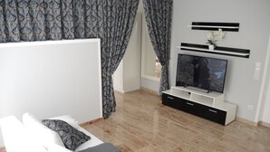 A modern living room with a white sofa, patterned cushions, a flat-screen TV, and a minimalist entertainment unit. - Merkel Villa Apartamente (Wiesbaden)