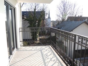 A balcony with a metal railing and a view of a church spire in the background.