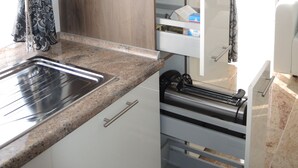 A modern kitchen with a built-in oven, a stainless steel sink, and a wooden cabinet. - Merkel Villa Apartamente (Wiesbaden)