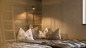 Una habitación acogedora con pared de madera, una escalera y una cama con almohadones estampados.