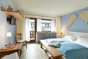 Une chambre à coucher avec un lit, un bureau, une chaise, un téléviseur et une fenêtre avec des rideaux.