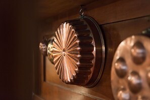 Gros plan sur une poignée de porte métallique à motifs festonnés et sur une plaque de porte ronde, à surface texturée.
