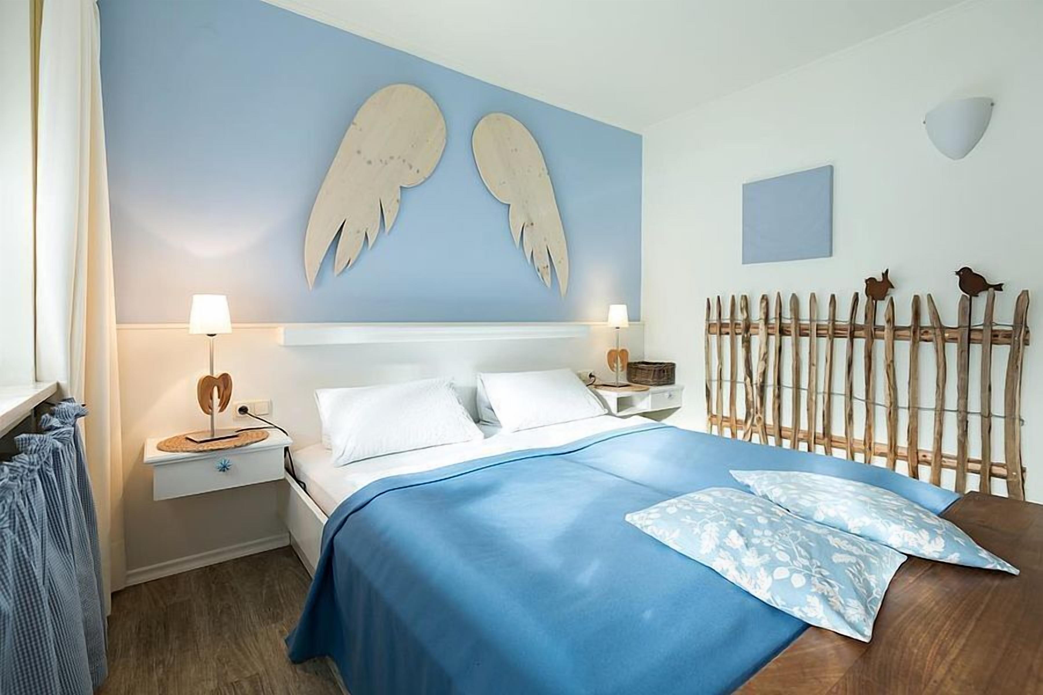 Un dormitorio con una cama, dos mesitas de noche, una lámpara de pared, un cabecero de madera y un adorno en la pared.