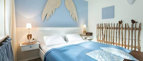 Un dormitorio con una cama, dos mesitas de noche, una lámpara de pared, un cabecero de madera y un adorno en la pared.